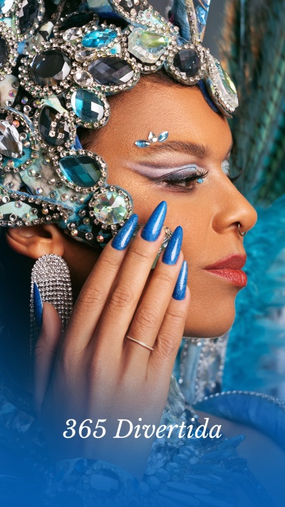 Pessoa com maquiagem e acessórios faciais azuis e brilhantes, unhas azuis metálicas longas, acessórios prateados e texto '365 Divertida'.