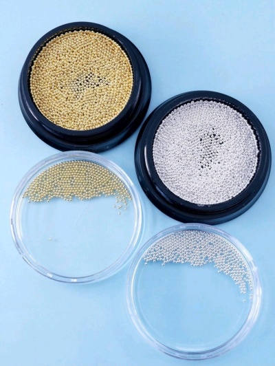 Recipientes com pérolas douradas e prateadas para nail art em fundo azul