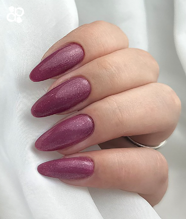 Mão com unhas almendradas pintadas de rosa escuro brilhante segurando tecido branco