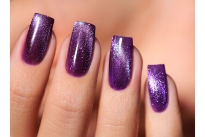 Unhas com verniz roxo brilhante e cintilante em quatro dedos