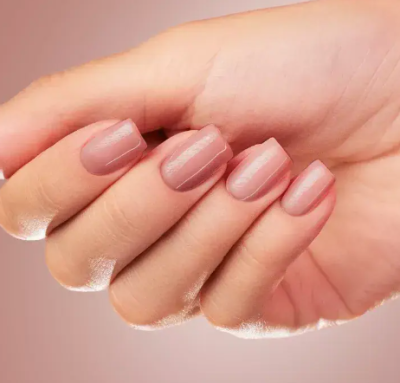 Mão feminina com unhas rosa nude brilhantes e formato quadrado