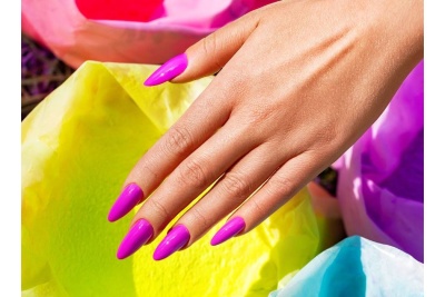 Mão feminina com unhas rosa vibrantes sobre papéis coloridos.