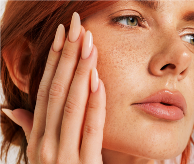 Close-up rosto mulher ruiva com unhas artificiais nude brilhante