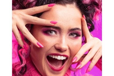 Retrato de mulher feliz com maquilhagem, unhas e cabelo cor-de-rosa
