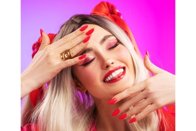 Mulher loira maquiagem rosa, batom e unhas vermelhas com laço vermelho no cabelo