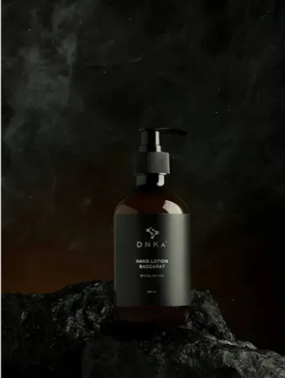 Frasco âmbar de loção para mãos DNKA Baccarat com válvula preta sobre pedra escura
