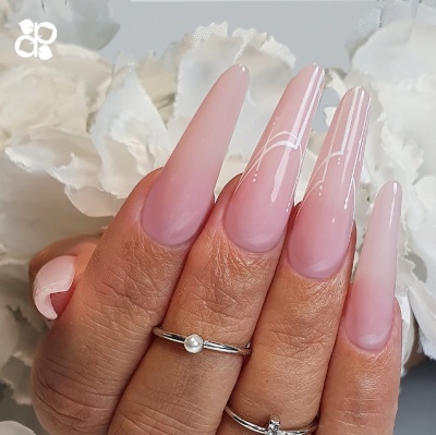 Unhas longas rosa com detalhes brancos e anéis prateados, mãos femininas com flores brancas ao fundo