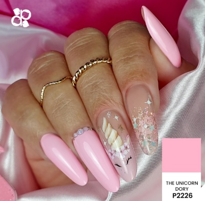 Unhas cor-de-rosa com decoração de unicórnio e detalhes brilhantes em fundo de cetim rosa
