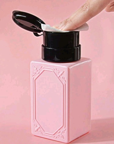 Frasco quadrado rosa com tampa preta contendo discos de algodão.