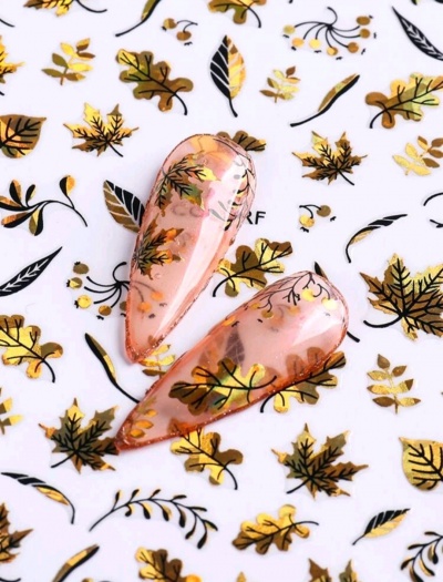 Acessórios para unhas transparentes com padrão de folhas douradas, pretas e castanhas sobre fundo branco decorado