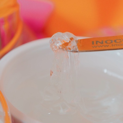 Gel transparente em recipiente branco com espátula laranja