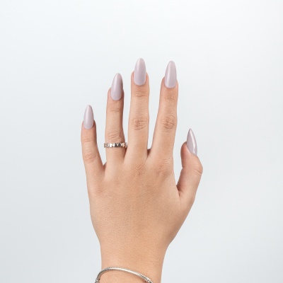 Mão feminina com unhas cinza claro e anel prateado em fundo branco