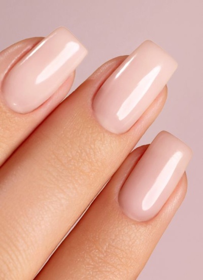 Unhas com esmalte nude brilhante em fundo rosa claro