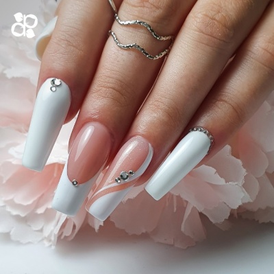 Manicure de unhas compridas com esmalte branco e rosa nude com decoração de pedras prateadas