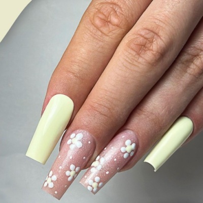 Unhas longas decoradas com esmalte amarelo claro e flores brancas em fundo rosa translúcido