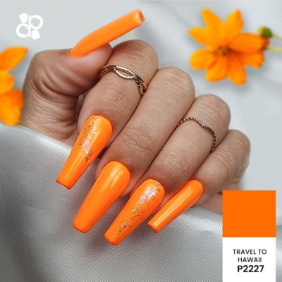Unhas artificiais laranja com detalhes florais, anéis prateados e flores ao fundo