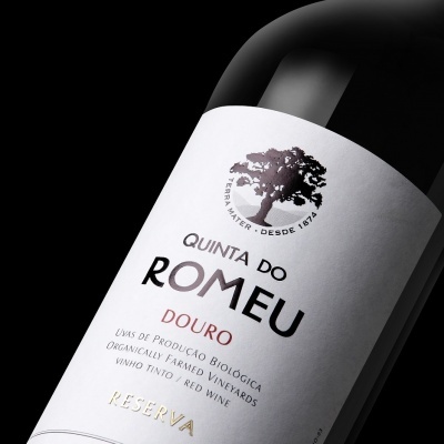 Garrafa de vinho tinto com rótulo branco e texto preto vermelho e dourado