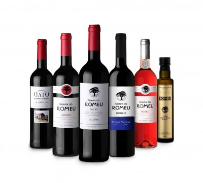 Conjunto de seis garrafas, cinco de vinho de várias cores e uma de azeite, com rótulos brancos e detalhes coloridos.