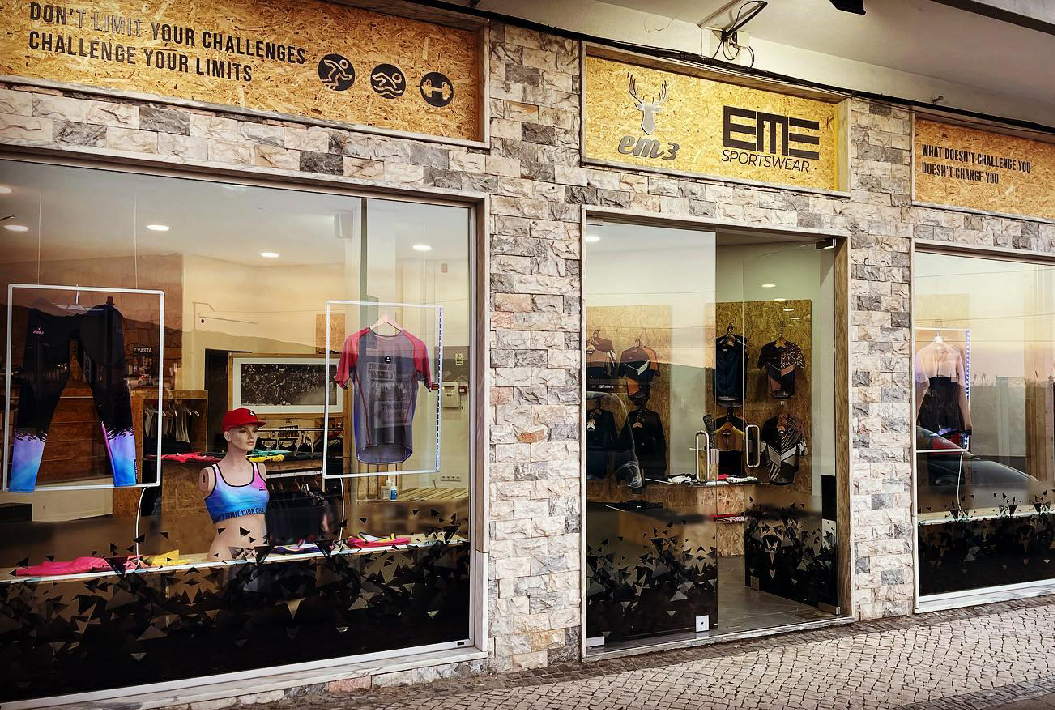 Montras de loja desportiva com manequins vestindo roupa colorida e sinais exteriores com texto