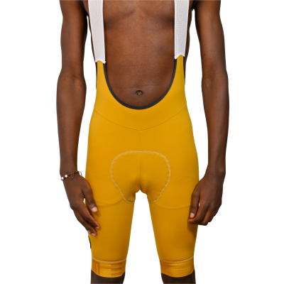 Calções de ciclismo amarelos com tiras brancas, detalhe da costura reforçada no assento