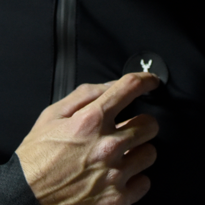 Mão a tocar botão com símbolo de veado em roupa preta