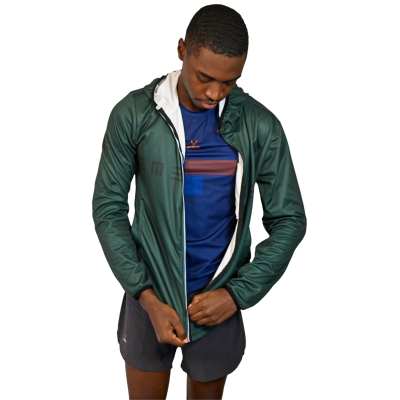 Homem a vestir casaco verde escuro, camisola azul riscada e calções pretos