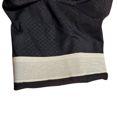 Detalhe de tecido preto com padrão cruzado cinzento e faixa elástica branca