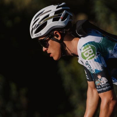 Capacete de ciclismo branco com texto, usado por ciclista com óculos e roupa de ciclismo colorida