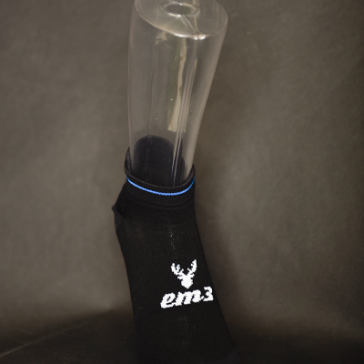 Meias pretas curtas com logo 'em3' branco e faixa azul clara num suporte transparente