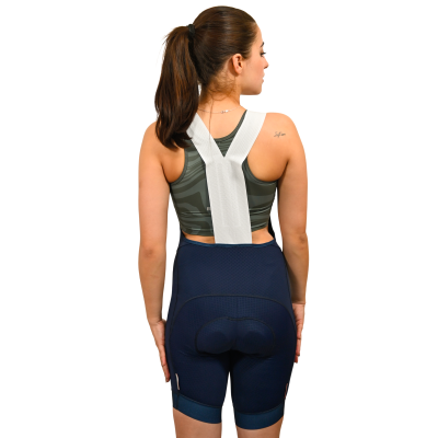 Mulher de costas com calções de ciclismo azuis escuros, alças brancas e top desportivo verde-escuro