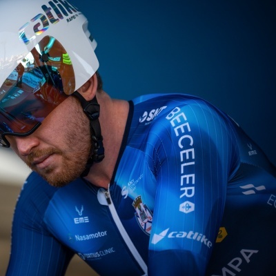 Ciclista com fato técnico azul e capacete branco com viseira espelhada