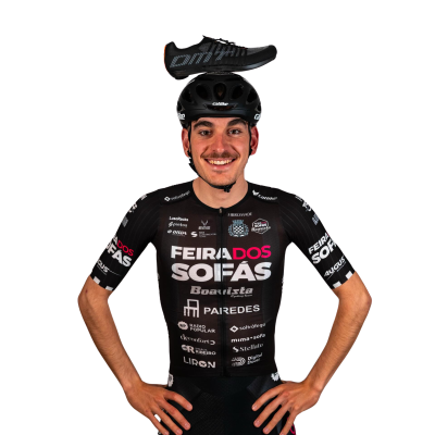 Homem de fato de ciclismo preto com logotipos, capacete preto e sapatilha preta na cabeça