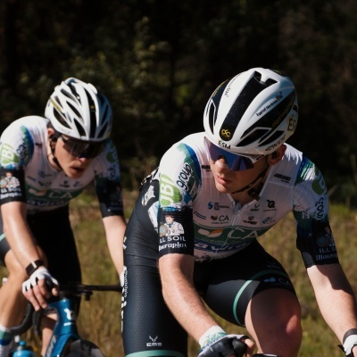 Dois ciclistas com roupa técnica e capacete branco a pedalar ao ar livre