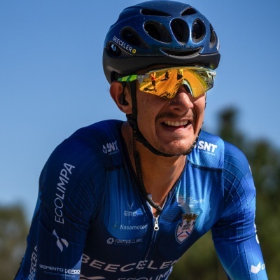 Ciclista com capacete azul e óculos espelhados a usar camisola azul com logos