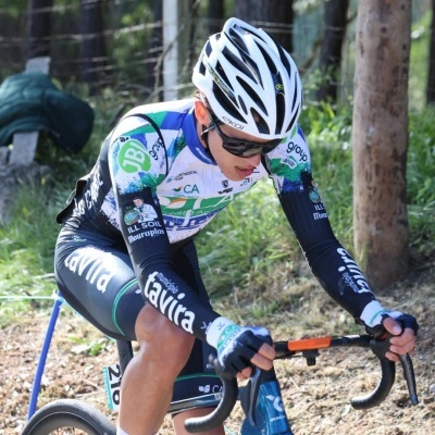 Ciclista com roupa desportiva colorida e capacete branco a pedalar bicicleta azul na floresta