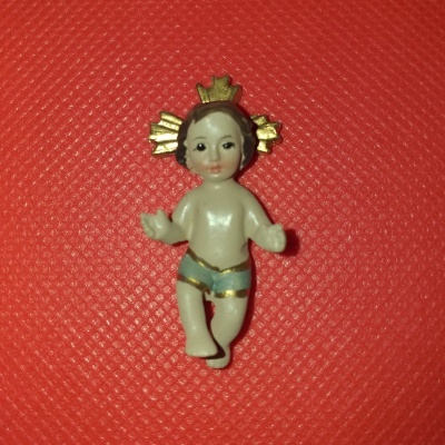 Figurinha bebé Jesus com auréola dourada sobre fundo vermelho