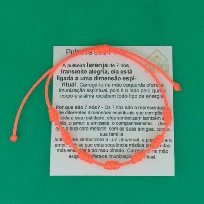Pulseira laranja com 7 nós sobre uma cartolina branca com texto em português e fundo verde.