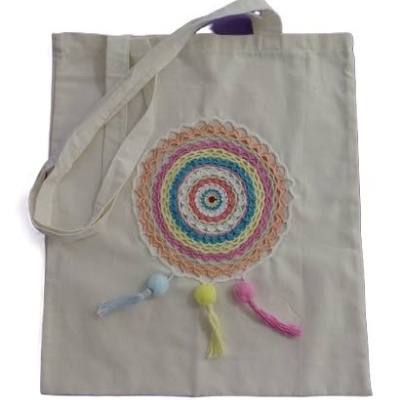 Saco de pano bege com decoração em croché colorida e pompons