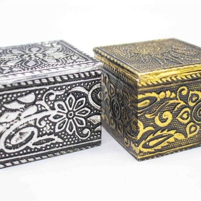 Duas caixas quadradas decorativas em metal, uma prateada e outra dourada, com padrões florais gravados.