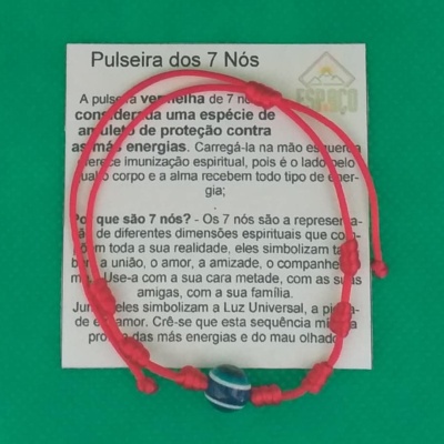 Pulseira vermelha de corda com nó e conta azul com padrão branco, sobre papel explicativo.