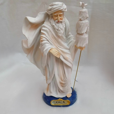 Escultura branca de homem com turbante segurando bastão, base azul com inscrição OXALÁ.