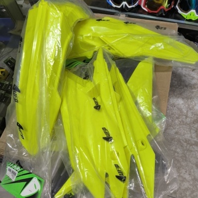 Peças plásticas amarelas para motocicleta marca UFO embaladas em plástico transparente.