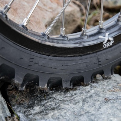 Pneu de bicicleta preto com cravos e aro prata com raios metalicos em cima de pedra cinzenta