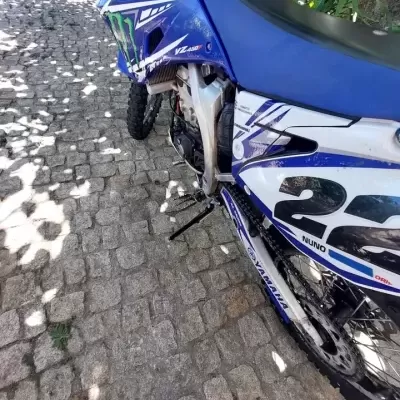 Motocross azul e branco com número 22 estacionada em calçada portuguesa