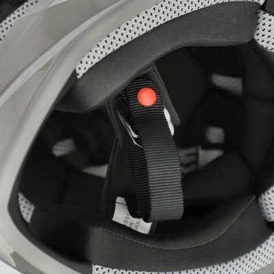 Interior de capacete cinza com acolchoamento preto e branco e fita preta com botão vermelho