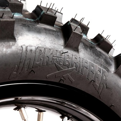 Pneu preto com cravos grandes e texto em relevo 'JACK THE GRIPPER'