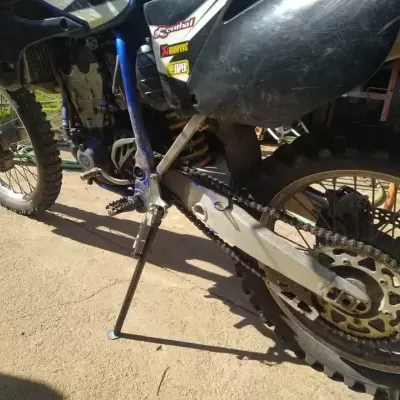 Motocross preta com quadro azul e autocolantes RENTHAL, AKRAPOVIC e TAPER