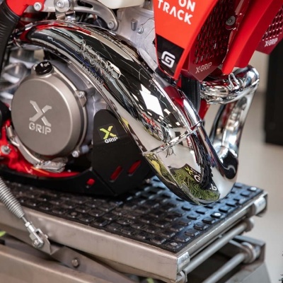 Escape cromado e motor de moto com autocolantes X GRIP, motor cinzento, elementos vermelhos, plataforma metálica preta