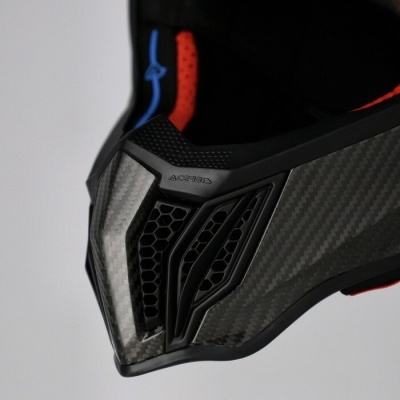 Capacete em fibra de carbono preto com detalhes vermelhos e entrada de ar em padrão favo de mel