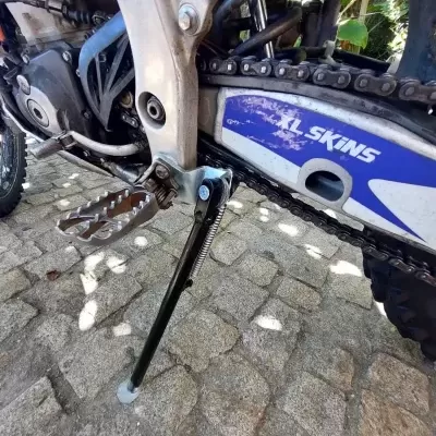 Detalhe da lateral de uma moto de motocross com descanso e proteção azul XL SKINS
